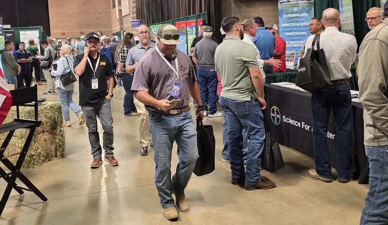 A packed trade show aisle between sessions on Day 1, attendees walking and talking between booths